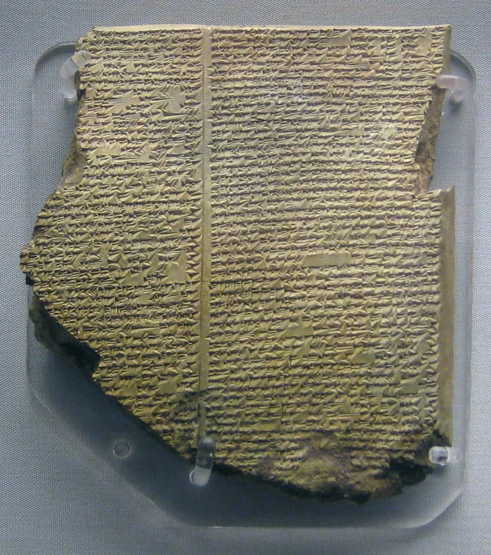 The Flood Tablet: a cracked clay tablet from Nineveh covered in cuneiform, held upright on a museum mount